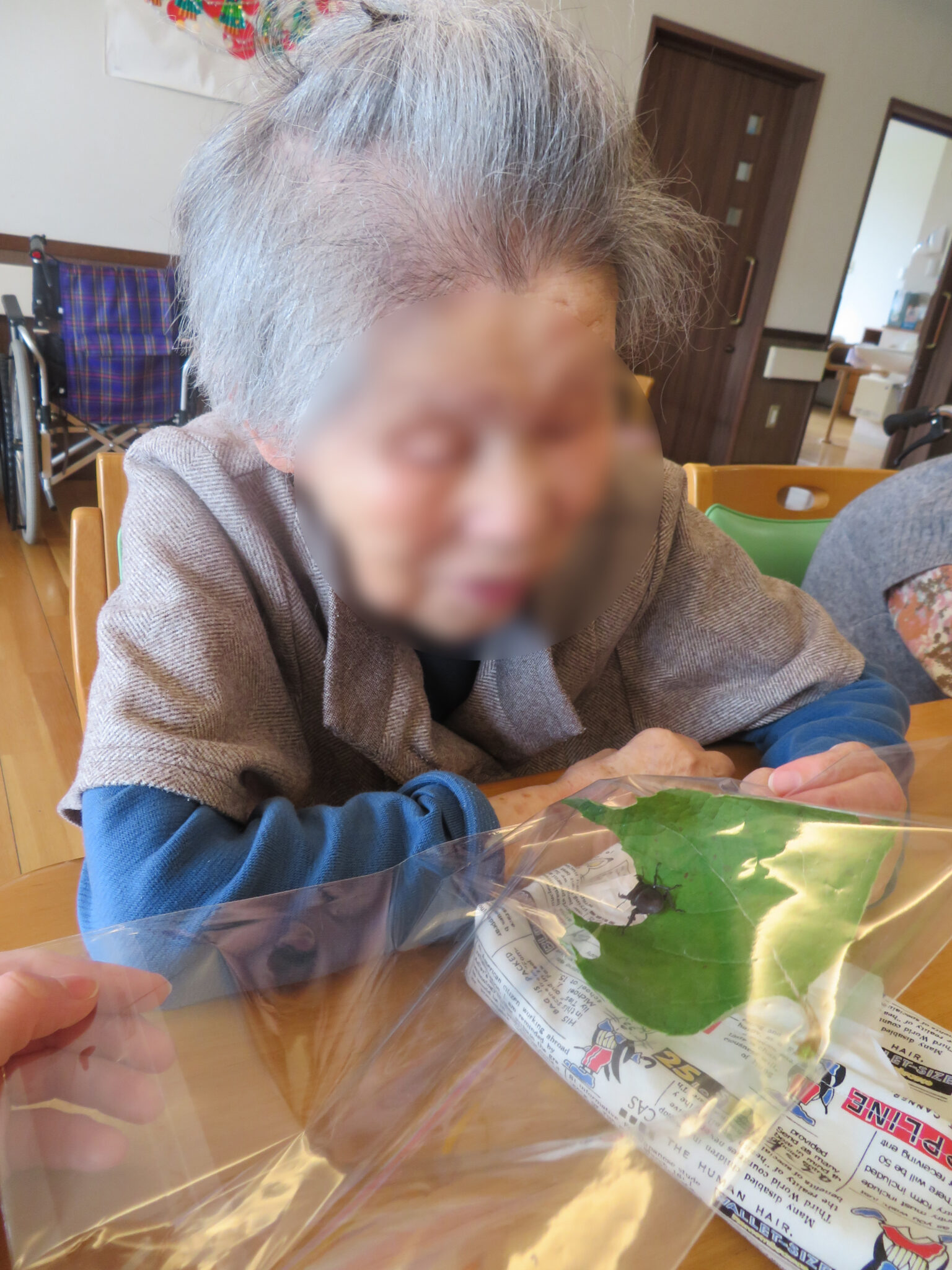 入居者が新聞を見ながら活動している様子。テーブルでの日常的な生活風景。